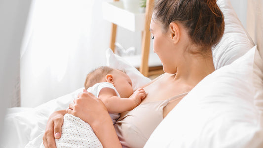 white mom breastfeeding baby on the bed