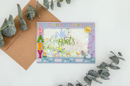 image of a handmade paper congratulations shaker card that has baby written inn colorful wood letters, and the inside has confetti 