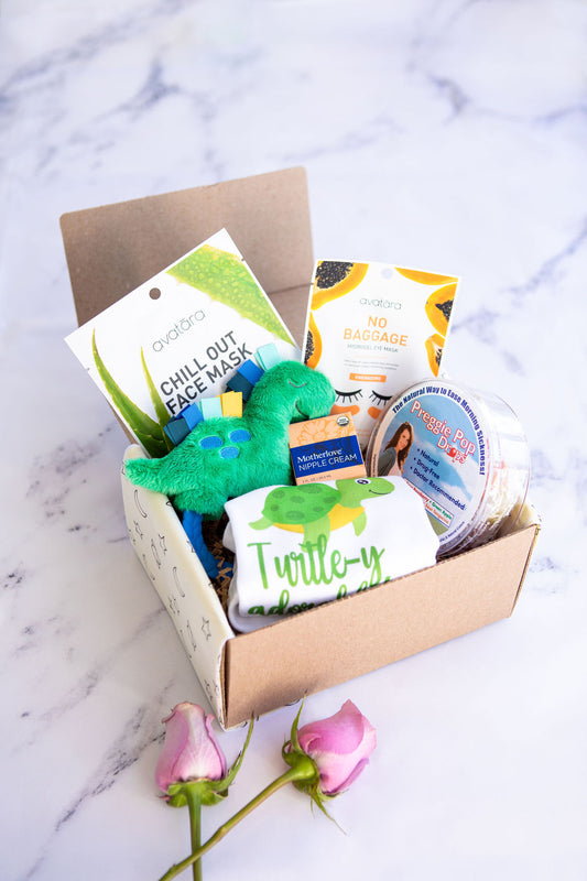 image of the welcome baby boy gift box that has the turtle-y adorable onnesie, the dinosaur rattle, preggie pop drops, motherlove nipple cream, and the avatara chillout face mask and no baggage eye mask