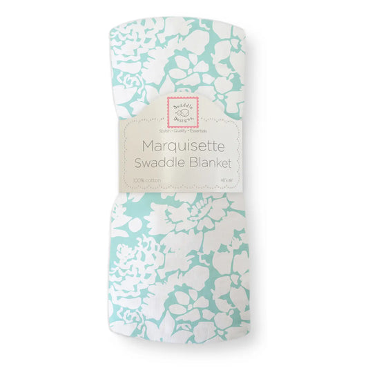 picture of the marquisette swaddle blanket in packaging where you see the torquoise  background with a white flower pattern
