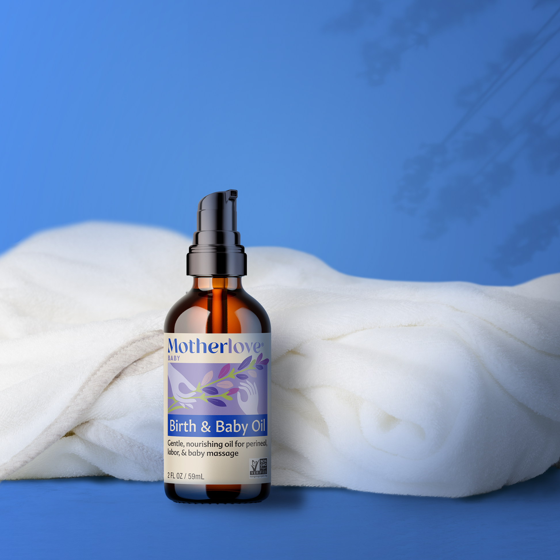 picture of a bottle of motherlove birth and baby oil with a white blanket behind it on a bluebackground