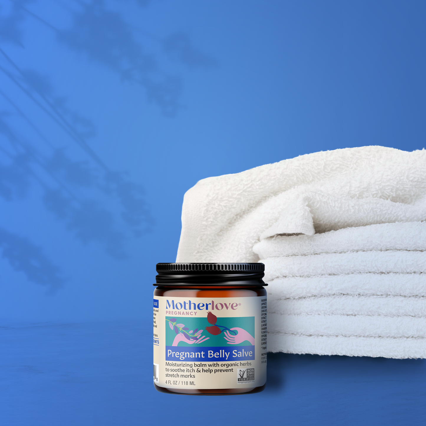 picture of a jar of motherlove pregnant belly salve in front of a stack of white towels with a blue background